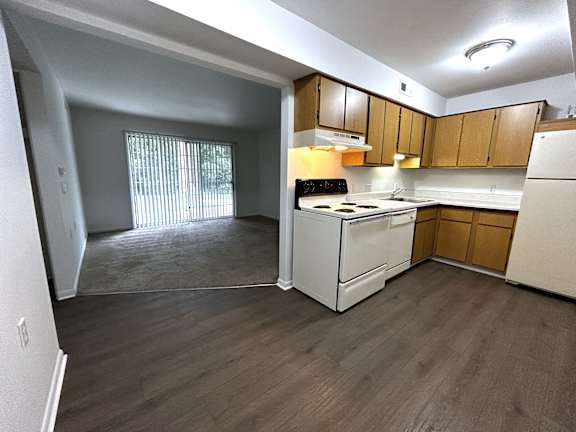 A kitchen with white appliances and wooden cabinets.