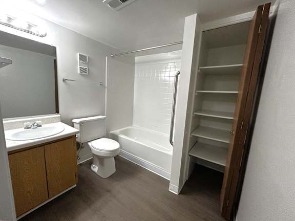 A white toilet sits in a bathroom with a walk-in shower.