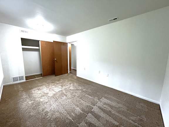 A bedroom with a carpeted floor and a brown door.