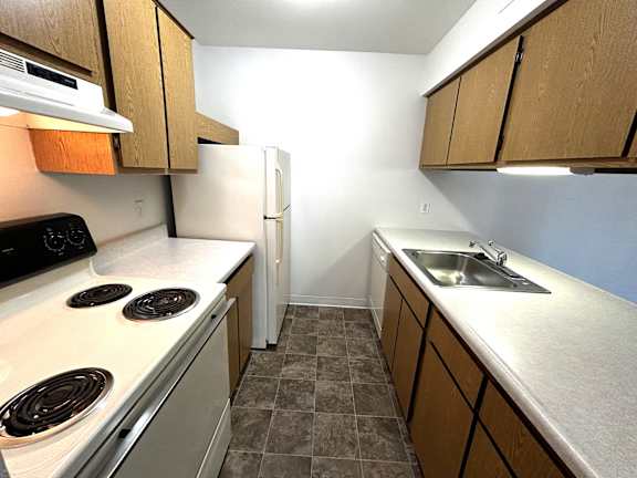 A kitchen with a white stove top oven, white counter top, and a white refrigerator.
