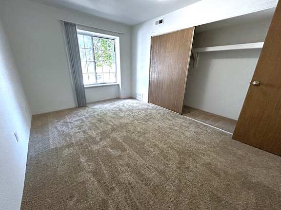 A befdroom with a carpeted floor and a window.