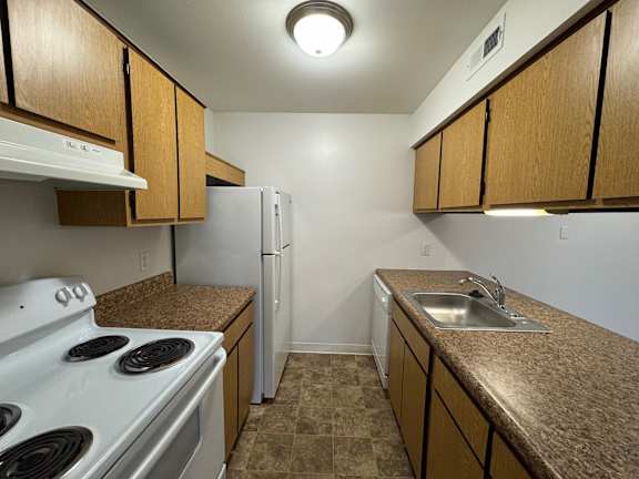 A kitchen with a white stove and a white refrigerator.