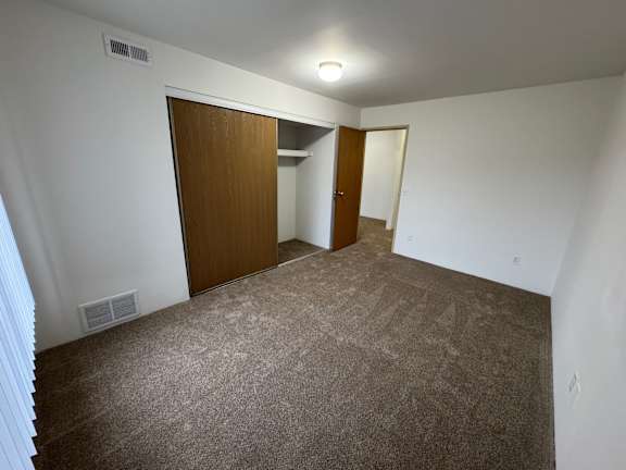 A bedroom with a carpeted floor and two doors.