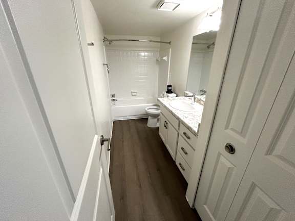 A white bathroom with a sink, toilet and shower.