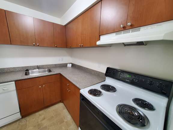 A kitchen with a white stove and wooden cabinets.