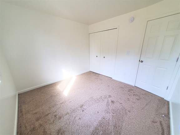 A bedroom with carpeted floor and two white doors.