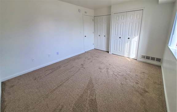A bedroom with carpeted floor and two white doors.