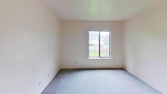 A bedroom with a large window and carpeted floor A bedroom with a large window and carpeted floor at Briarwood Apartments in Benton Harbor, MI