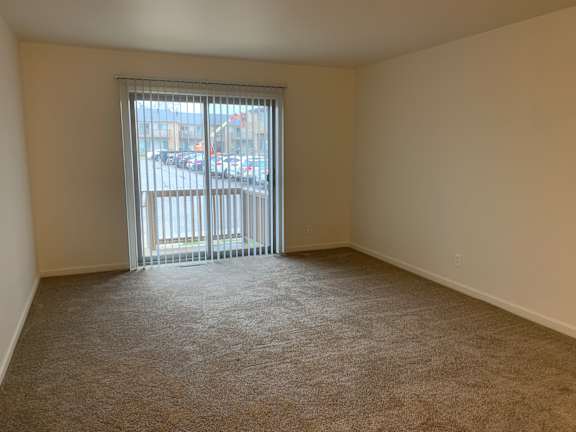 A room with a carpeted floor and a sliding glass door.