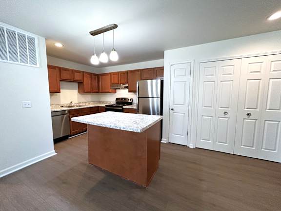 A kitchen with a white island and wooden cabinets.