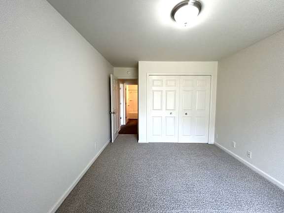 A bedroom with a white door and carpeted floor.