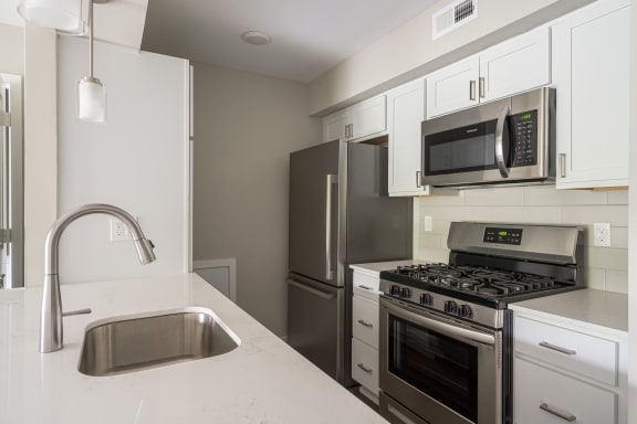 a kitchen with white cabinets and stainless steel appliances at Hillside Apartments, Wixom, MI