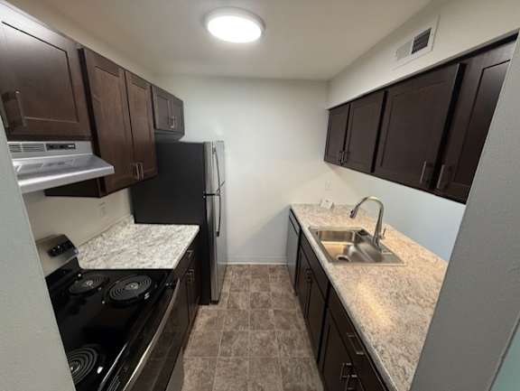 A kitchen with brown cabinets and a black refrigerator.