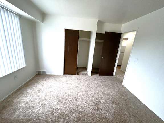 A bedroom with carpeted floor and two open doors.