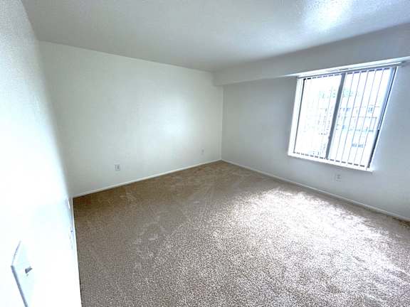 A bedroom with a carpeted floor and a window with bars on it.