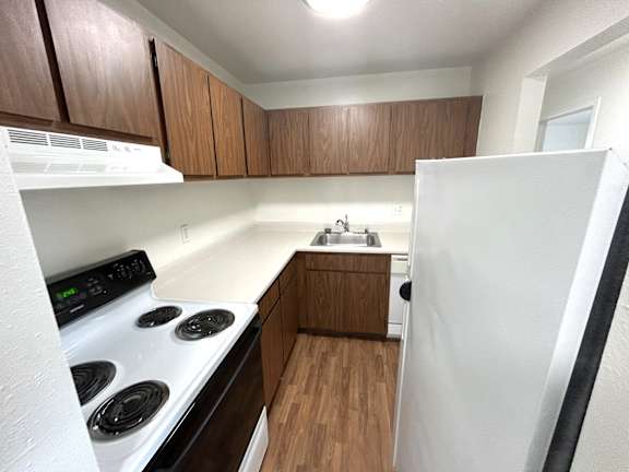 A kitchen with a white stove top oven and a white refrigerator.