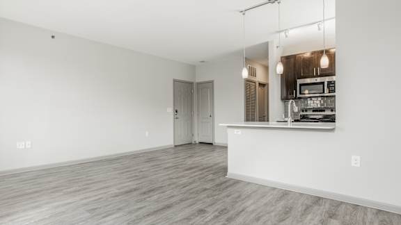 A spacious room with a kitchenette and a door leading to another room.