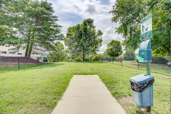 a walkway to a dog park with a blue trash can on it at Sunscape Apartments, Roanoke