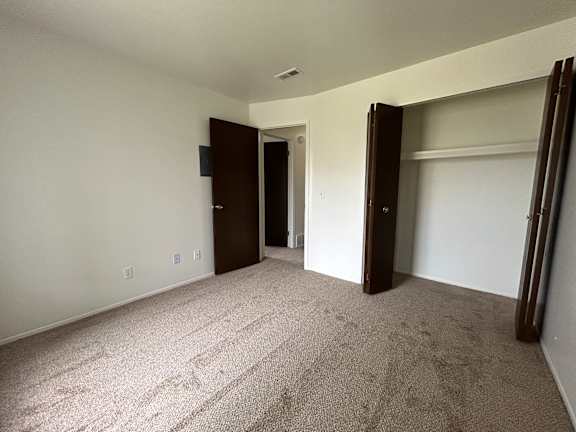 A carpeted bedroom with a door and a wall socket.