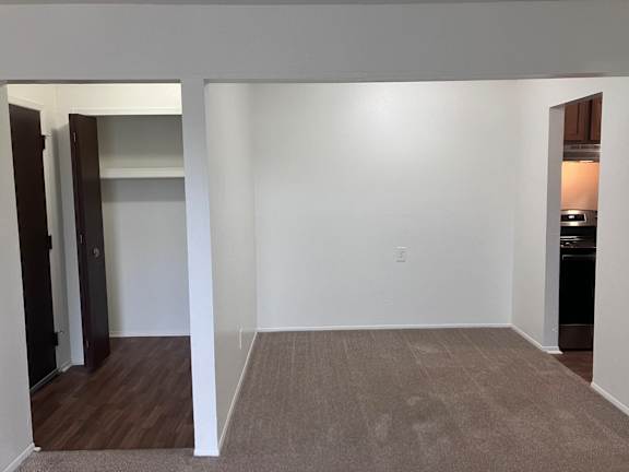 A dining room with a carpeted floor and white walls.