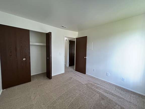 A bedroom with carpeted floor and two doors.