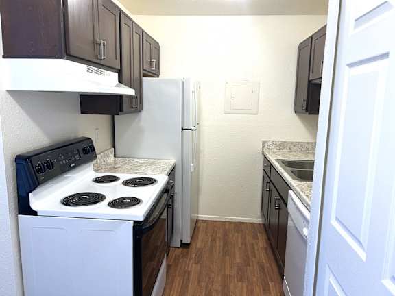 Galley kitchen with white appliances and granite counters at Huntington Place Apartments, Essexville, 48732