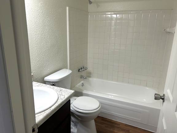 Bathroom with white tile surround and granite vanity at Huntington Place Apartments, Michigan
