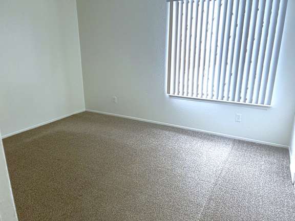 Empty carpeted bedroom with window and blinds at Huntington Place Apartments, Essexville, MI, 48732
