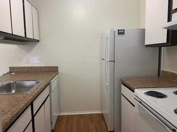 A kitchen with a white fridge, stove, and sink.