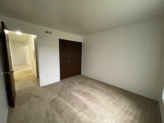 A bedroom with a brown door and carpeted floor.