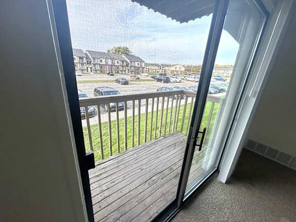 A view from a room looking out to a parking lot and houses.