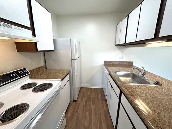 A kitchen with white appliances and brown countertops.
