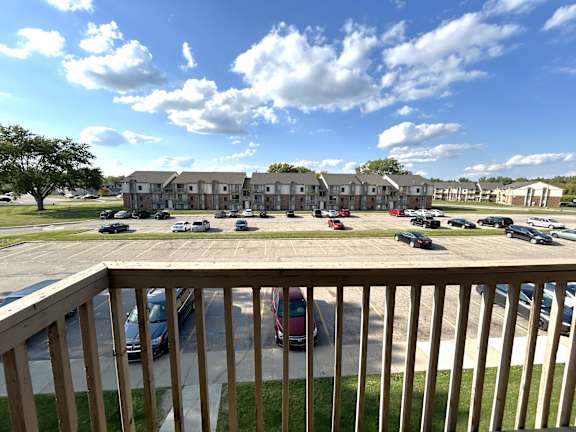 A grassy area and parking lot with cars and a building in the background.