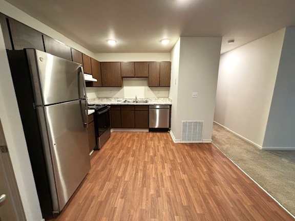 A kitchen with a refrigerator, stove, and sink.