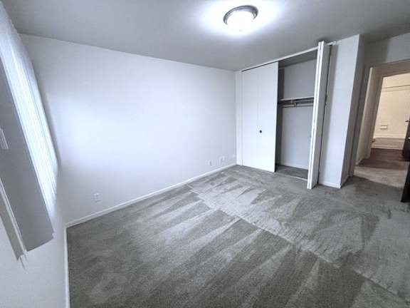 A bedroom with a carpeted floor and a white door.