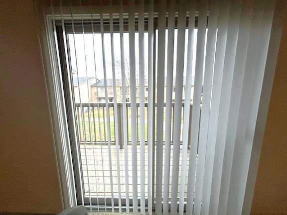 A view of a courtyard through a window with blinds.