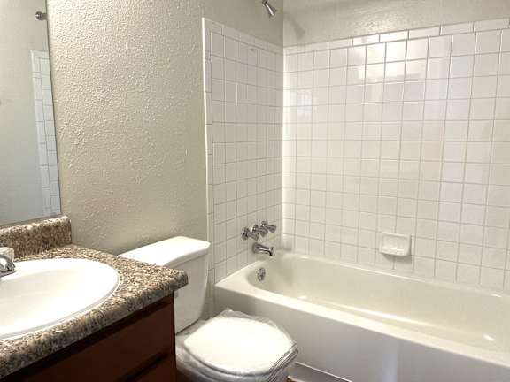 A white tiled bathroom with a sink, toilet, and bathtub.