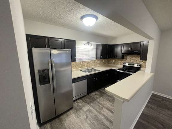 A kitchen with a stainless steel refrigerator and black cabinets