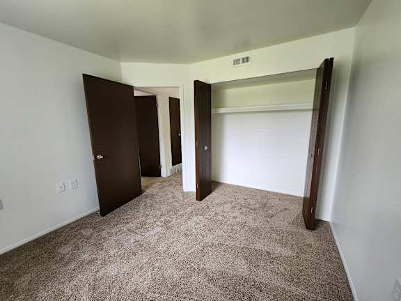 A bedroom with carpeted floor and a large closet.