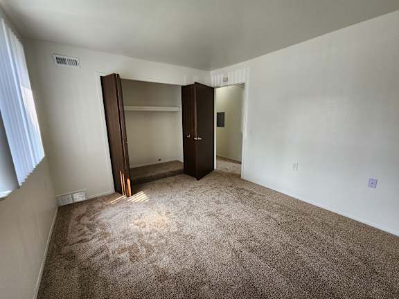 A bedroom with a carpeted floor and a large closet with a mirror.