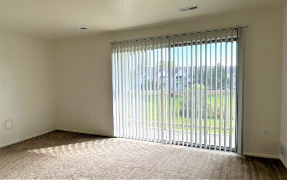 an empty living room with blinds on a window