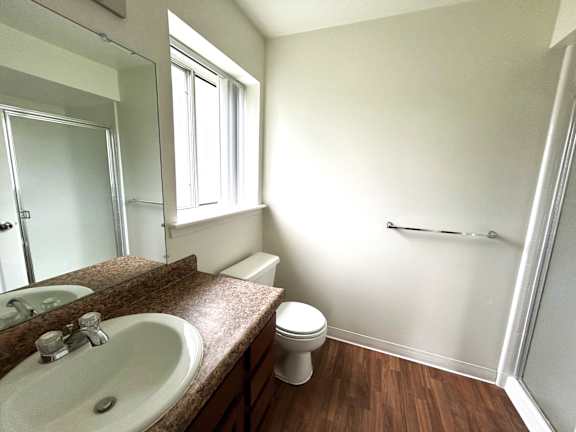 A bathroom with a toilet, sink, and mirror.