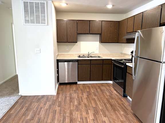 A kitchen with wooden cabinets and a stainless steel refrigerator.