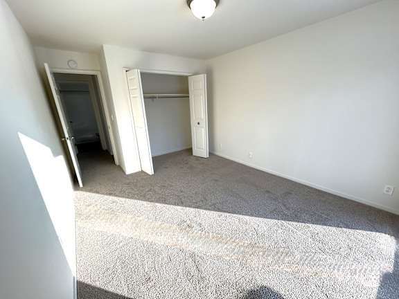 A bedroom with a carpeted floor and a closet.