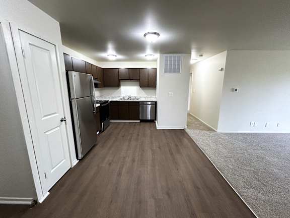 A kitchen with white appliances and brown flooring.