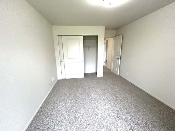 A bedroom with a carpeted floor and white walls.