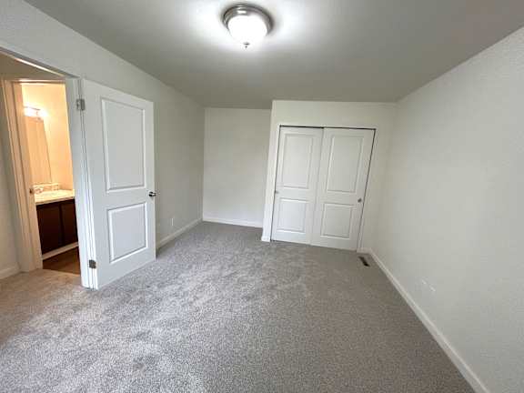 A bedroom with two doors and carpeted floor.