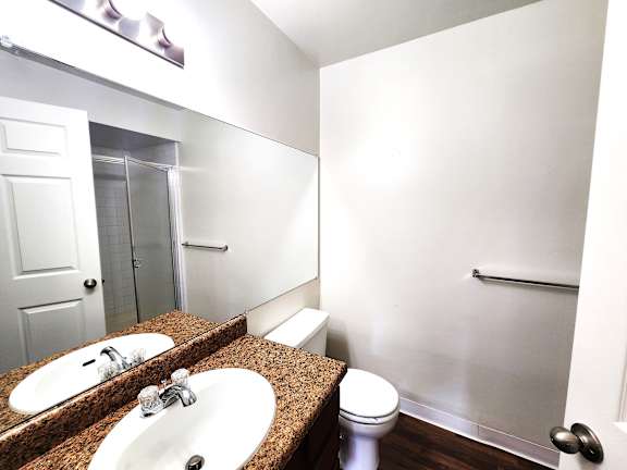 A bathroom with a toilet, sink and mirror.