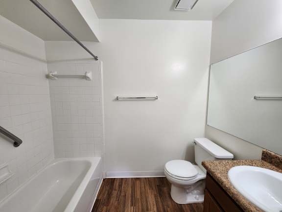 A white bathroom with a wooden floor and a white toilet.
