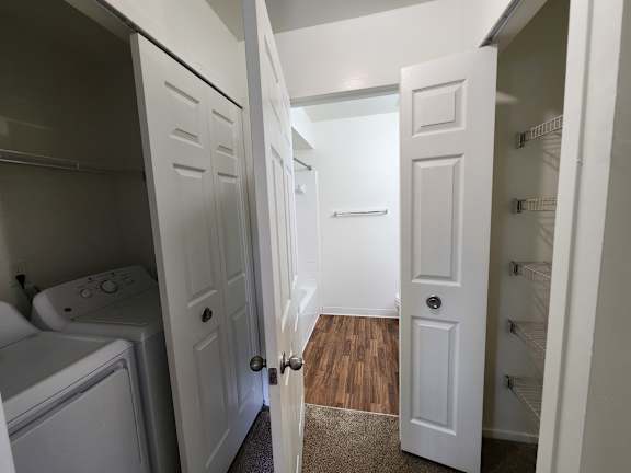 A white door is open to the in-unit washer and dryer.